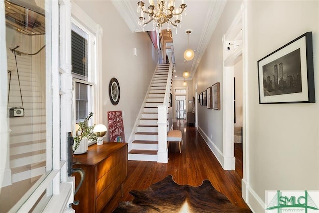 entryway with stairway, crown molding, wood finished floors, a chandelier, and baseboards