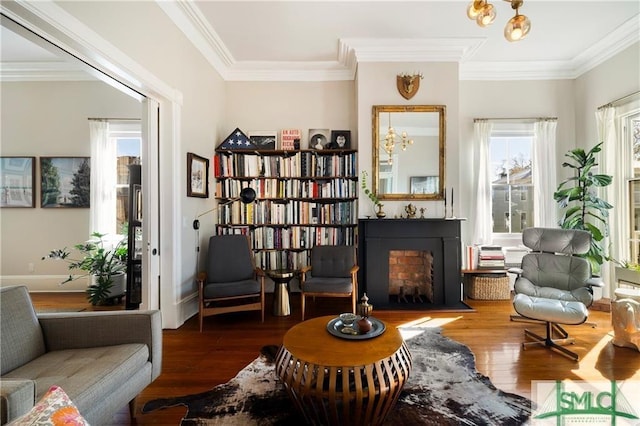 living area featuring a fireplace with flush hearth, hardwood / wood-style floors, and ornamental molding