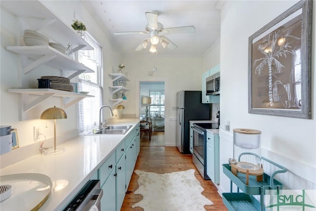 kitchen featuring open shelves, a sink, blue cabinets, light wood finished floors, and appliances with stainless steel finishes