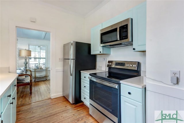 kitchen featuring light countertops, ornamental molding, light wood finished floors, and stainless steel appliances