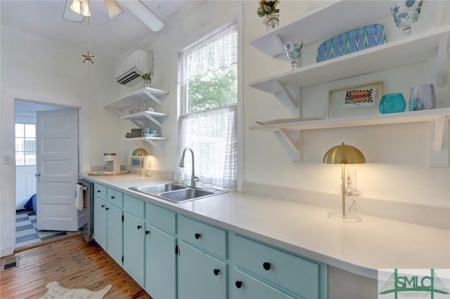 kitchen with open shelves, blue cabinets, a sink, light wood-type flooring, and a wall mounted AC