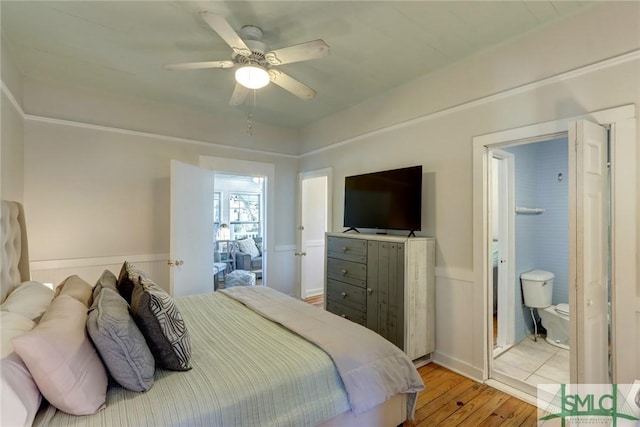 bedroom with wainscoting, light wood finished floors, and ceiling fan