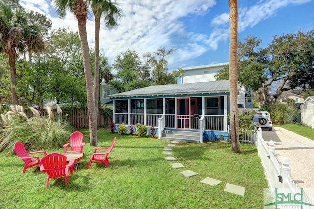 back of property featuring fence, a sunroom, a yard, and metal roof