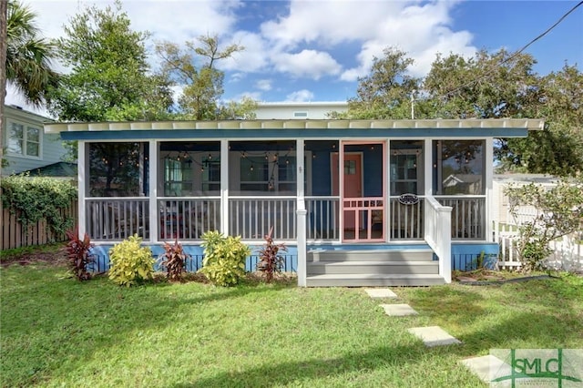 rear view of house featuring a sunroom and a lawn