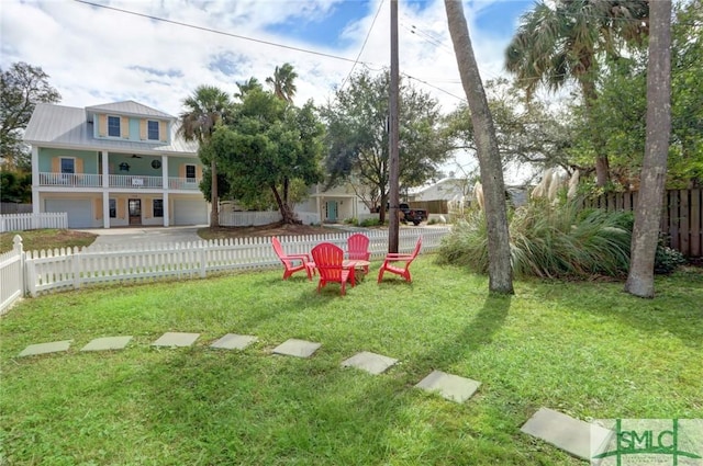view of yard with a balcony, driveway, fence private yard, and a garage