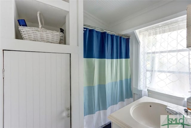 bathroom with a shower with curtain, crown molding, and a sink
