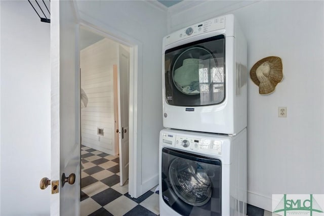 clothes washing area featuring tile patterned floors, stacked washer / dryer, and laundry area