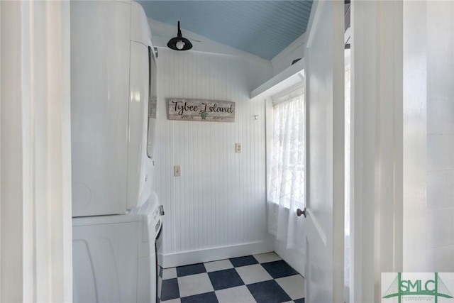 clothes washing area featuring tile patterned floors, stacked washing maching and dryer, and laundry area