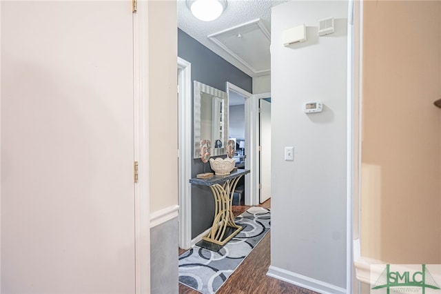 corridor with visible vents, attic access, a textured ceiling, and wood finished floors