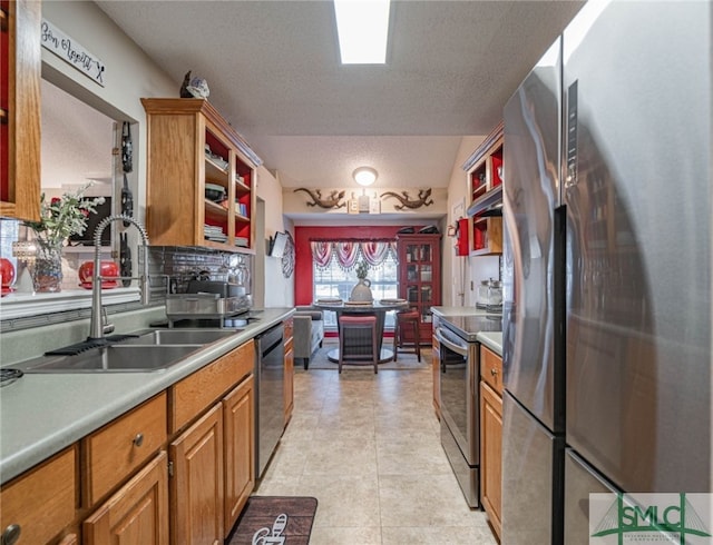 kitchen with a sink, open shelves, appliances with stainless steel finishes, and a textured ceiling