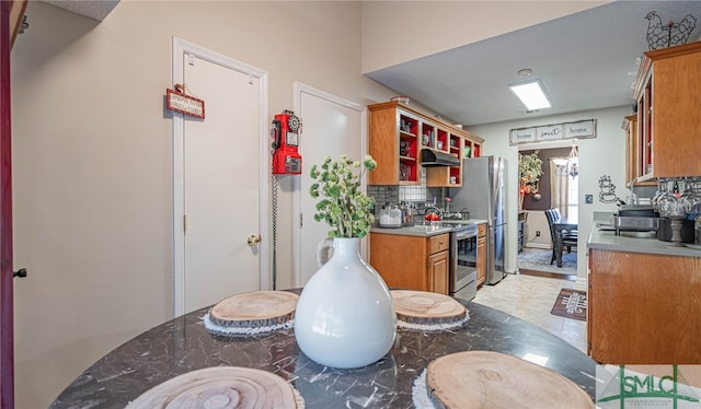 kitchen with decorative backsplash, open shelves, under cabinet range hood, brown cabinets, and stainless steel appliances
