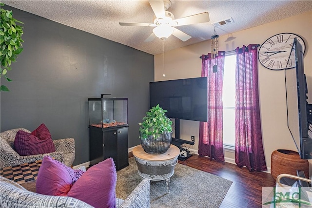 living room with visible vents, a ceiling fan, a textured ceiling, and wood finished floors
