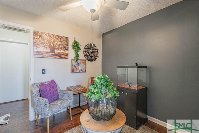 sitting room with visible vents, a ceiling fan, baseboards, and wood finished floors