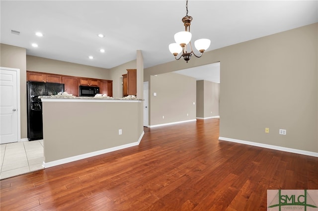 103 Regency Cir, Pooler, GA 31322 - kitchen with black appliances, brown cabinets, a chandelier, open floor plan, and light wood-type flooring