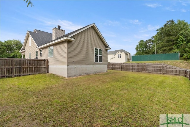 exterior space featuring a chimney, a fenced backyard, and a lawn