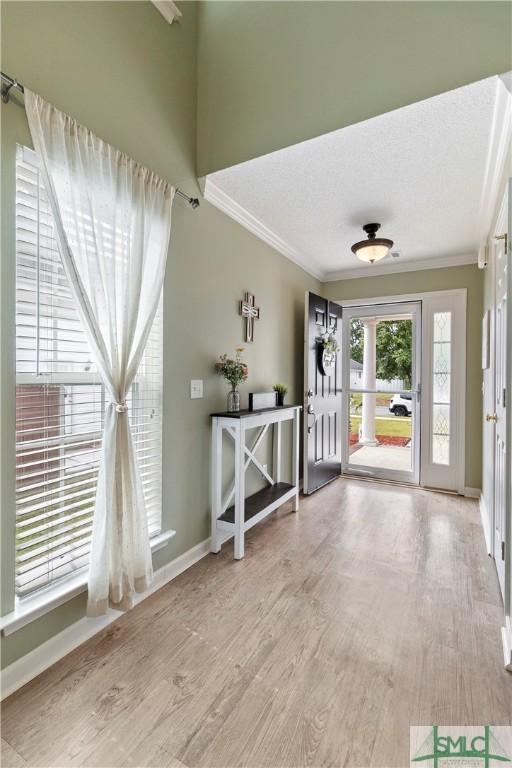 entrance foyer featuring baseboards, crown molding, and wood finished floors