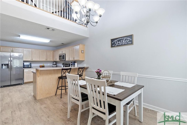 dining room featuring baseboards, an inviting chandelier, visible vents, and light wood-type flooring