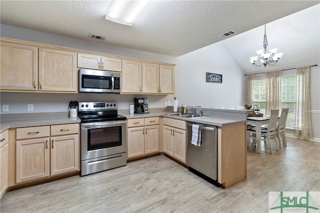kitchen featuring a peninsula, light brown cabinetry, stainless steel appliances, and visible vents