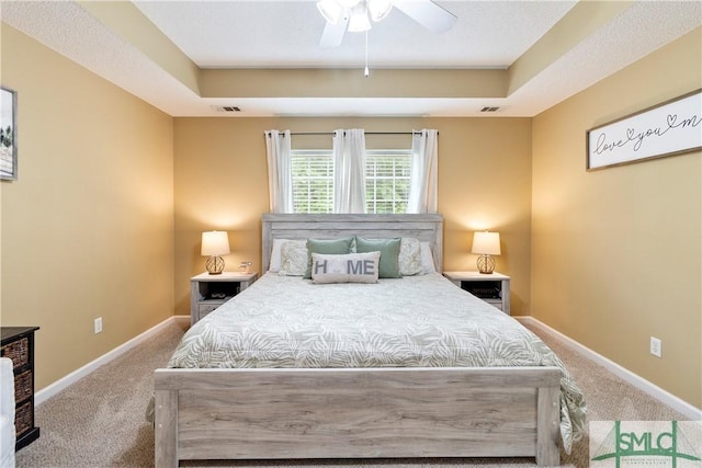 carpeted bedroom featuring a raised ceiling, visible vents, and baseboards