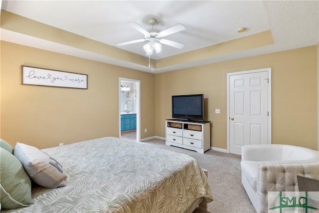 bedroom with a raised ceiling, a ceiling fan, light carpet, connected bathroom, and baseboards