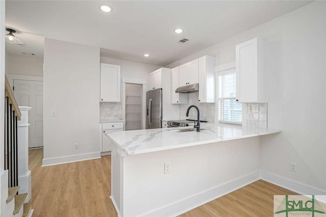 1203 E Bolton St, Savannah, GA 31404 - kitchen featuring light wood finished floors, a peninsula, stainless steel fridge, backsplash, and under cabinet range hood
