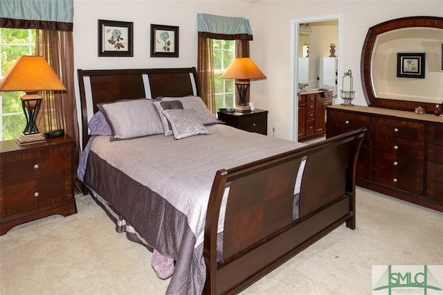 bedroom with connected bathroom and light carpet