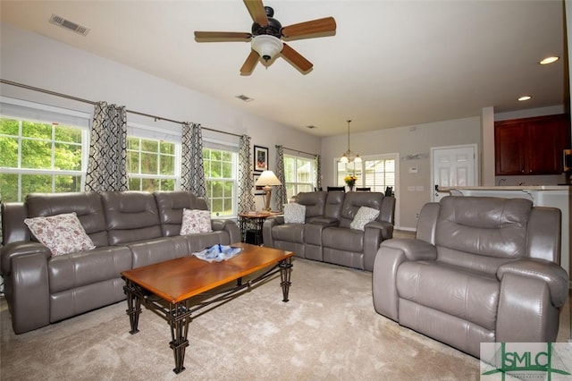 living area featuring ceiling fan with notable chandelier, visible vents, and a wealth of natural light