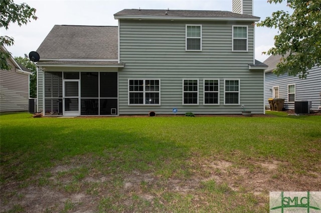 rear view of property featuring a yard, a sunroom, a chimney, and roof with shingles