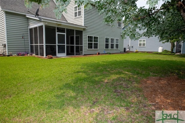 rear view of property with a lawn, a sunroom, and a shingled roof