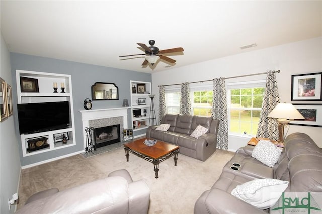 carpeted living area with a fireplace with flush hearth, baseboards, visible vents, built in features, and a ceiling fan