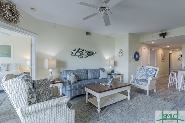 living room featuring wood finished floors, visible vents, and ceiling fan