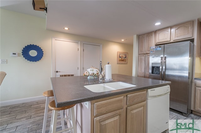 kitchen featuring a center island with sink, dark countertops, stainless steel fridge with ice dispenser, light brown cabinets, and dishwasher