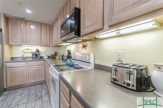 kitchen with white electric stove, dark countertops, light brown cabinetry, and stainless steel microwave