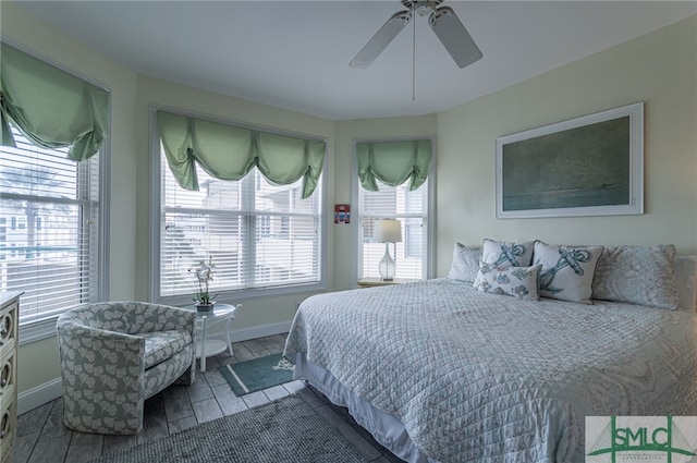 bedroom featuring wood finished floors, baseboards, ceiling fan, and multiple windows