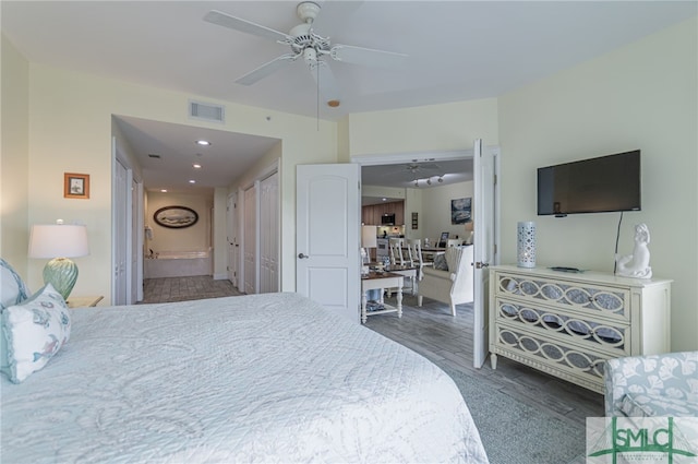 bedroom with wood finished floors, visible vents, ensuite bathroom, and ceiling fan