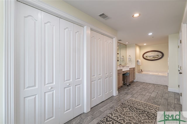 full bath featuring visible vents, recessed lighting, wood finished floors, a garden tub, and vanity