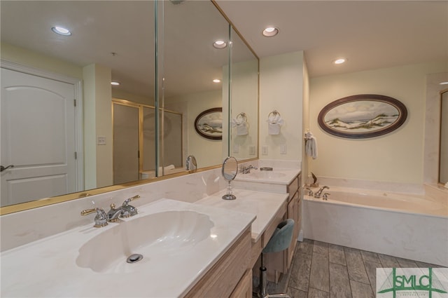 bathroom featuring a garden tub, wood finished floors, a sink, and double vanity