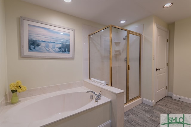 full bathroom with a shower stall, wood finished floors, a bath, baseboards, and recessed lighting