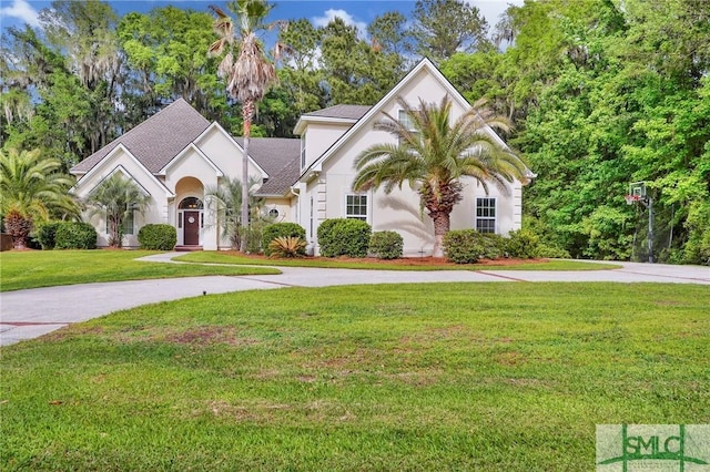 view of front of house with stucco siding, a front lawn, roof with shingles, and curved driveway