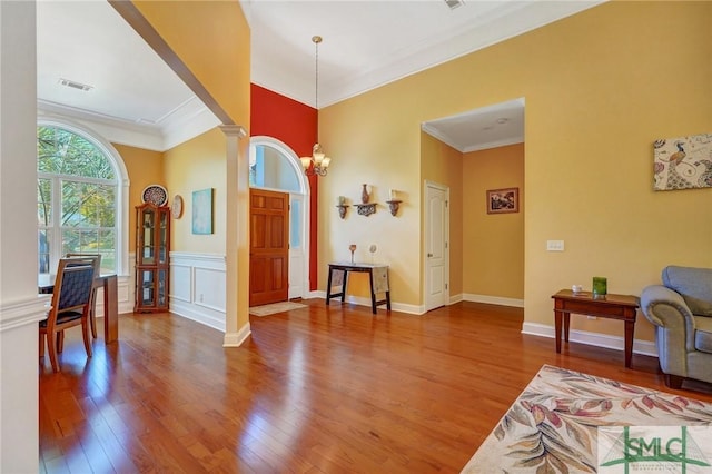 entryway featuring visible vents, decorative columns, wood finished floors, and crown molding