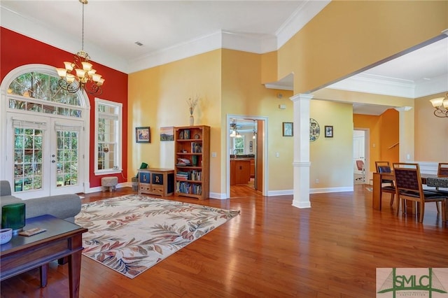 sitting room featuring a towering ceiling, wood finished floors, ornamental molding, french doors, and a chandelier