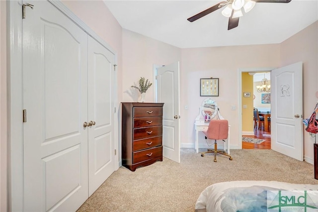 bedroom with baseboards, a closet, light colored carpet, and ceiling fan with notable chandelier