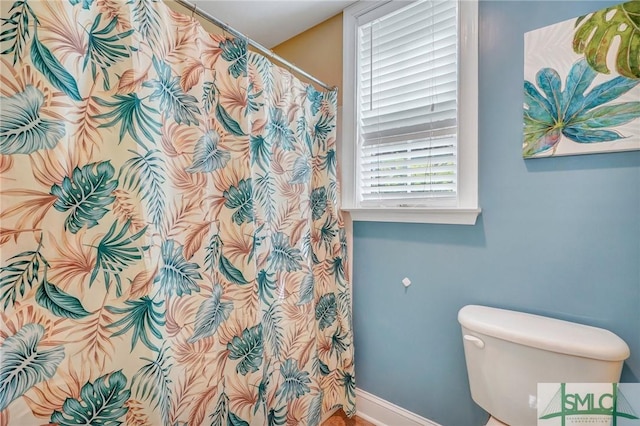 full bathroom featuring baseboards and toilet