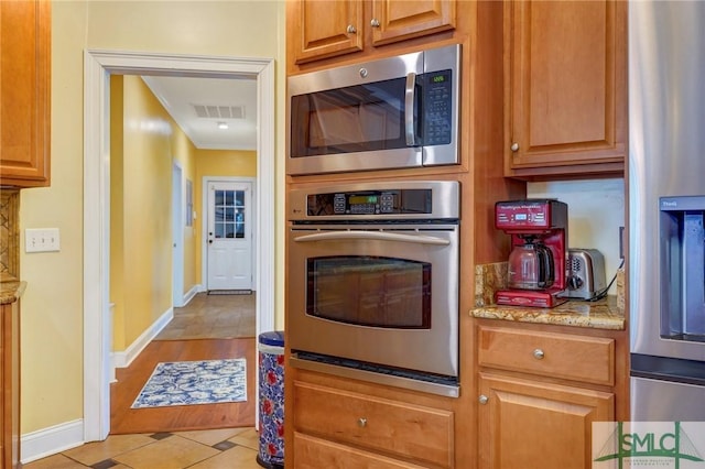 kitchen featuring stainless steel appliances, baseboards, visible vents, light stone countertops, and light tile patterned floors