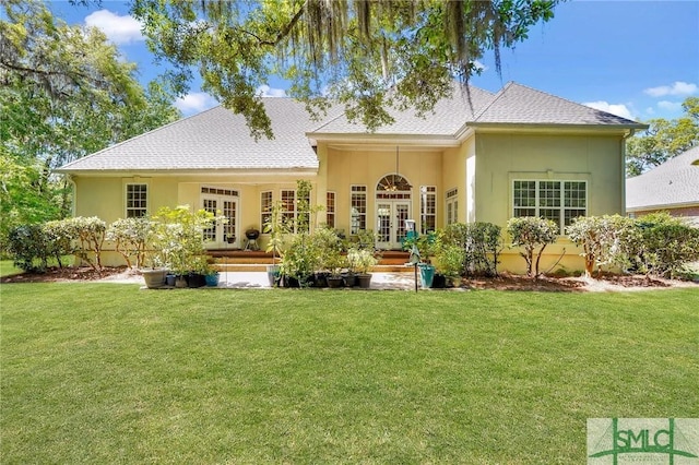 back of property with a yard, french doors, and stucco siding