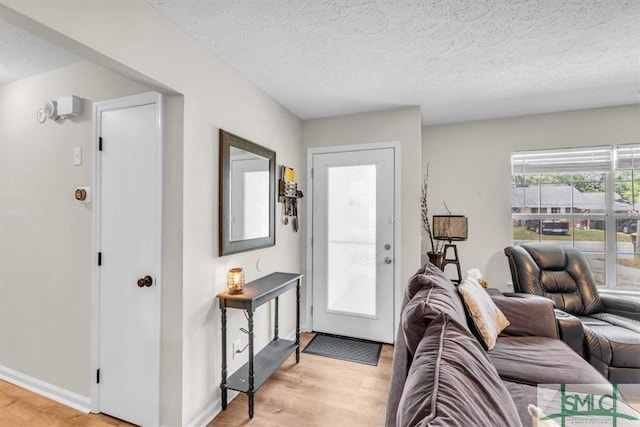 entrance foyer with light wood-style flooring, a textured ceiling, and baseboards