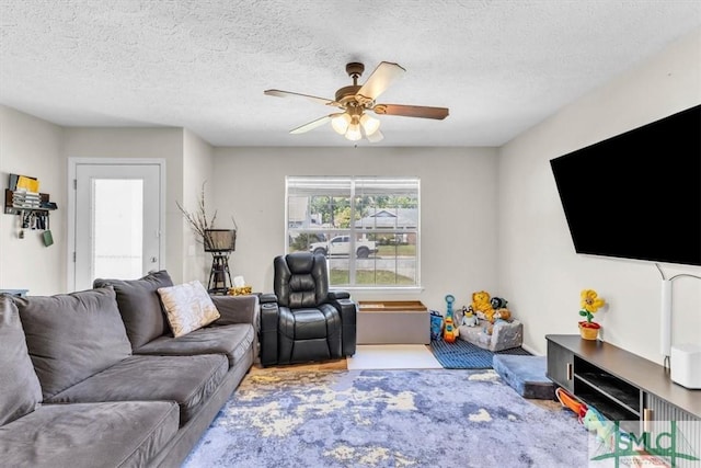 living room featuring ceiling fan and a textured ceiling