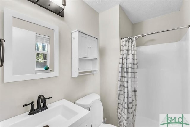 bathroom with a sink, toilet, a textured ceiling, and a shower with curtain