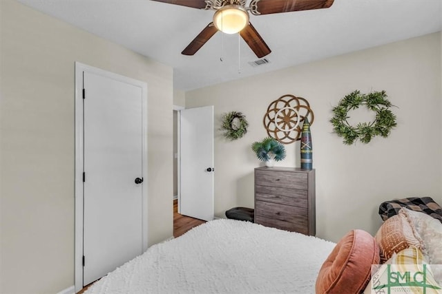 bedroom with baseboards, ceiling fan, visible vents, and wood finished floors
