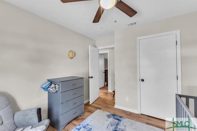 living area with visible vents, light wood-style floors, baseboards, a ceiling fan, and an upstairs landing